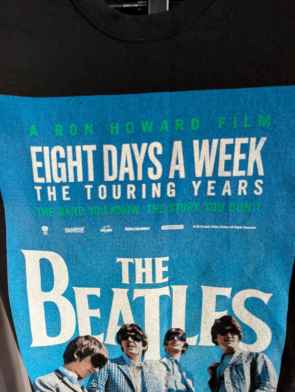 The Beatles black graphic tee featuring vibrant blue and white documentary print.