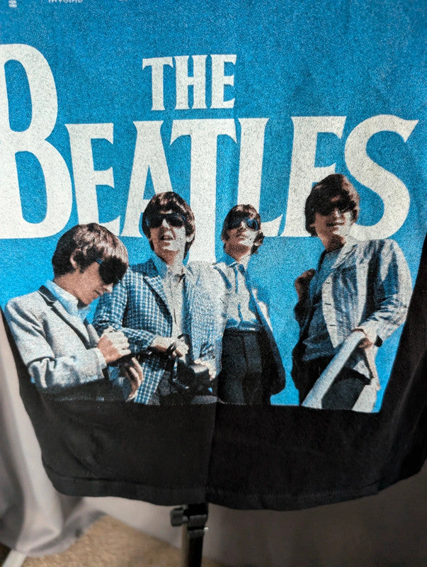 The Beatles black graphic tee featuring vibrant blue and white documentary print.