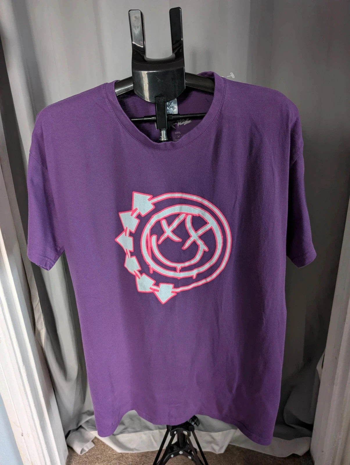 Blink-182 purple graphic tee featuring smiley face logo with neon pink outlining and drip detailing.