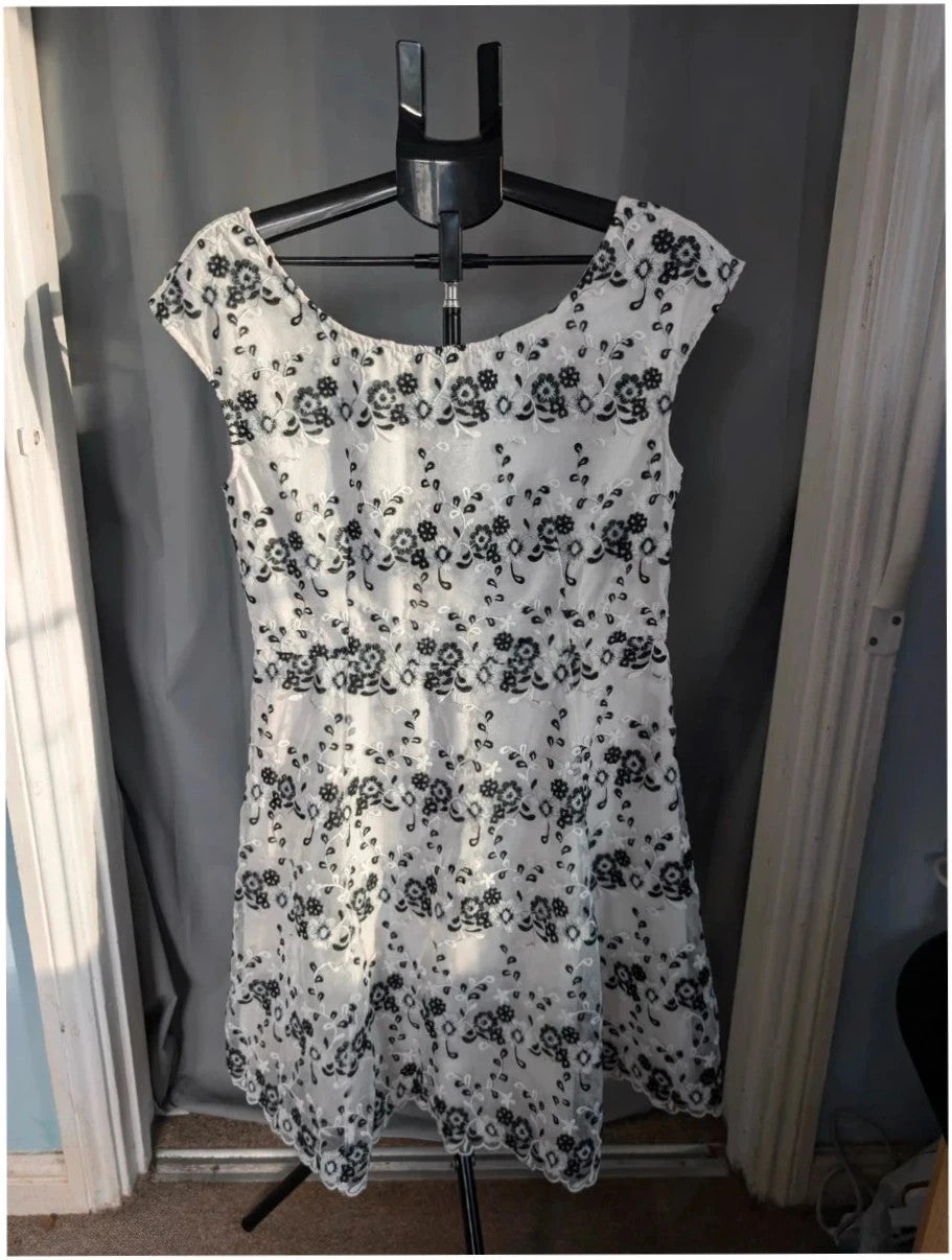 Yumi black and white floral embroidered mesh overlay dress with fitted waist and flared skirt.