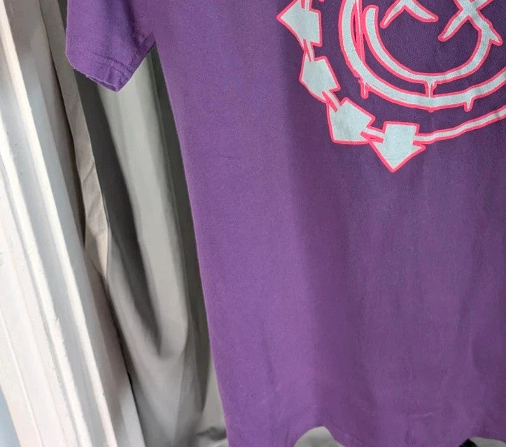 Blink-182 purple graphic tee featuring smiley face logo with neon pink outlining and drip detailing.