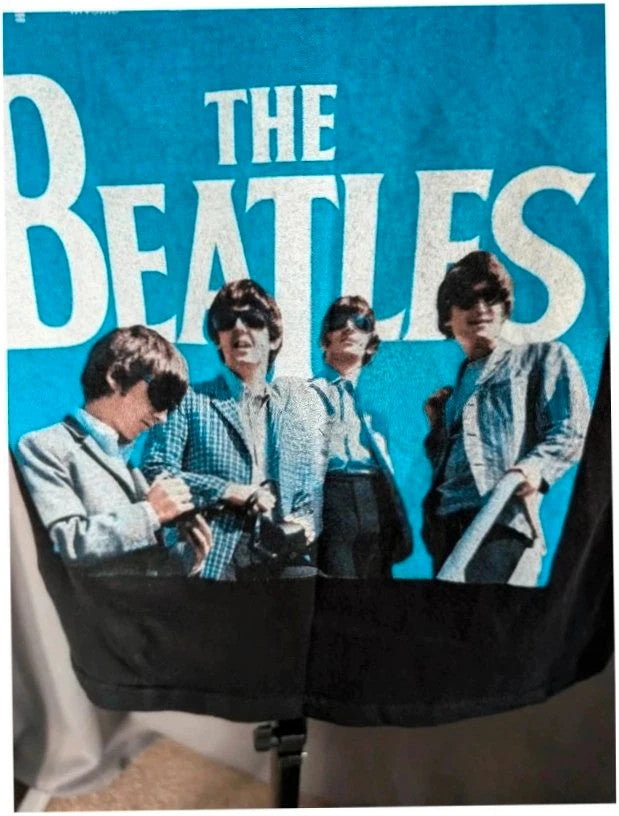 The Beatles black graphic tee featuring vibrant blue and white documentary print.