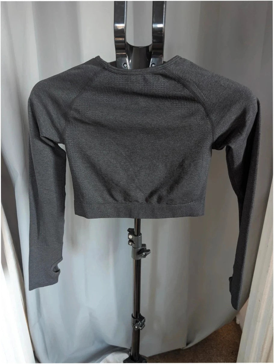 Pink Elephant black gym crop top with white logo, seamless design, and thumbhole cuffs.