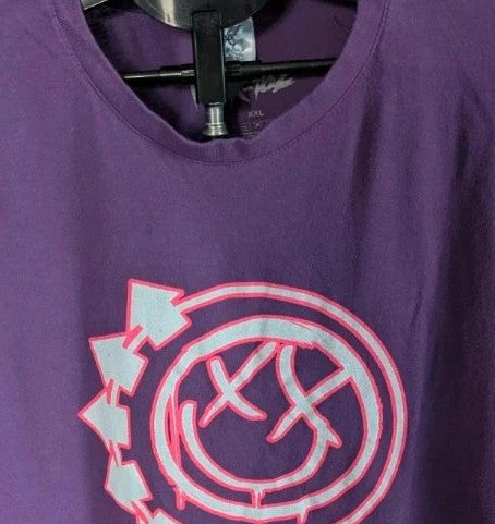 Blink-182 purple graphic t-shirt featuring smiley face logo with neon pink drip detailing.