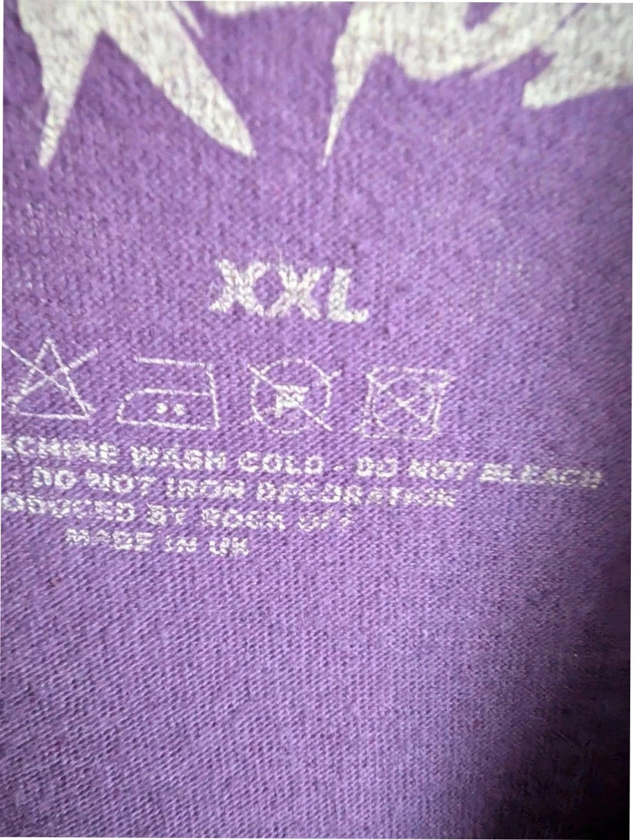 Blink-182 purple graphic t-shirt featuring smiley face logo with neon pink drip detailing.