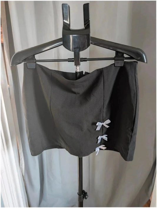 PrettyLittleThing black mini skirt with white satin bow detail and high-waisted fit.