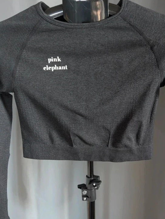 Pink Elephant black gym crop top with white logo, seamless design, and thumbhole cuffs.