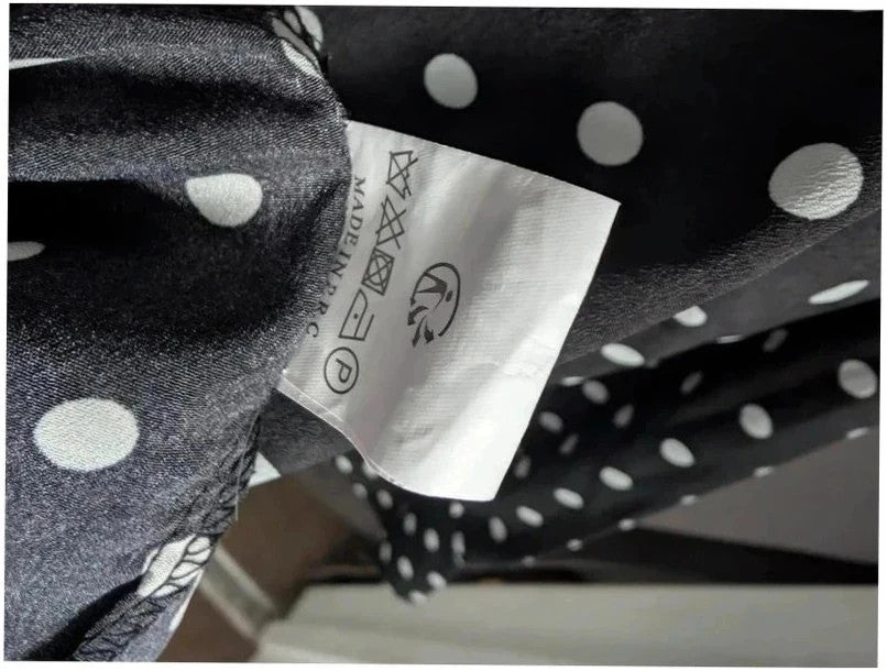 Voyelles black and white polka dot blouse with ruffle collar and button-up front.