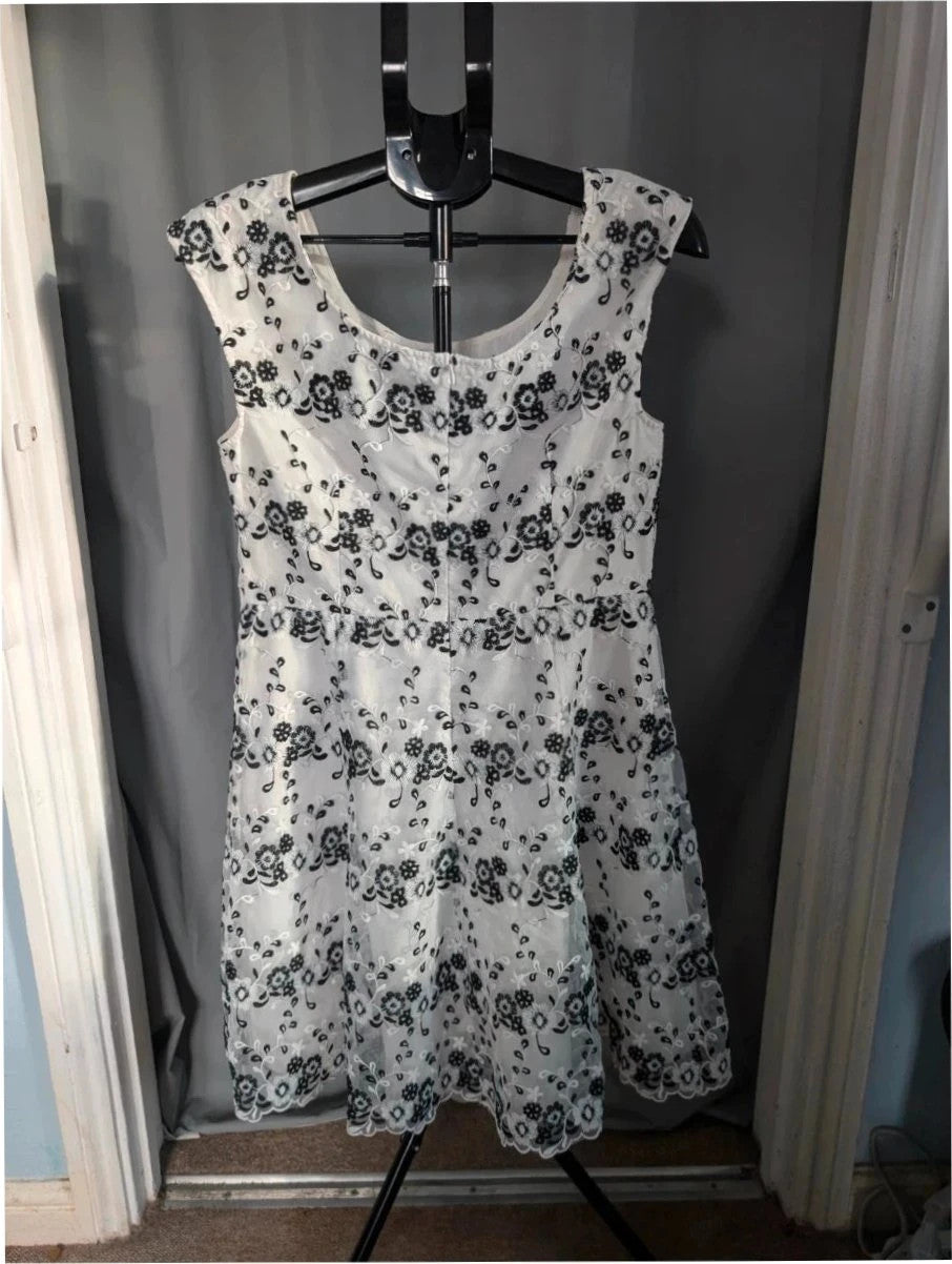 Yumi black and white floral embroidered mesh overlay dress with fitted waist and flared skirt.