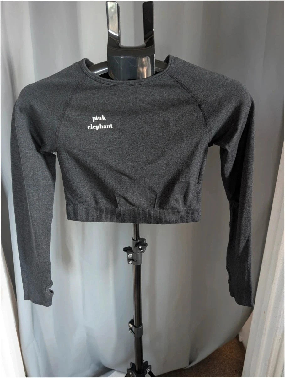 Pink Elephant black gym crop top with white logo, seamless design, and thumbhole cuffs.