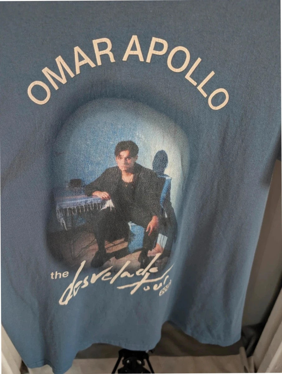Omar Apollo blue graphic tee featuring portrait print and tour date list on back.