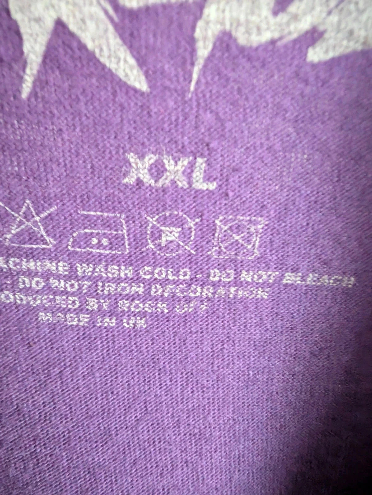 Blink-182 purple graphic tee featuring smiley face logo with neon pink outlining and drip detailing.