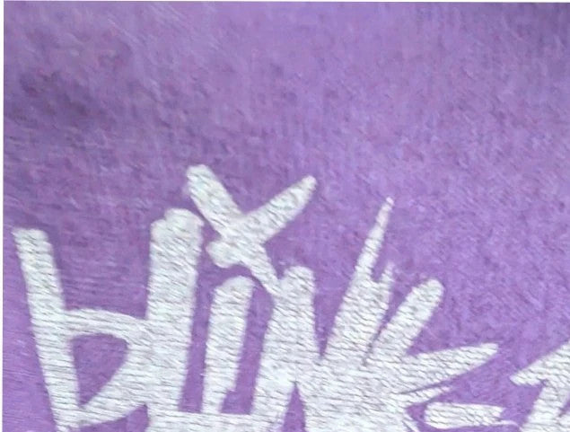 Blink-182 purple graphic t-shirt featuring smiley face logo with neon pink drip detailing.