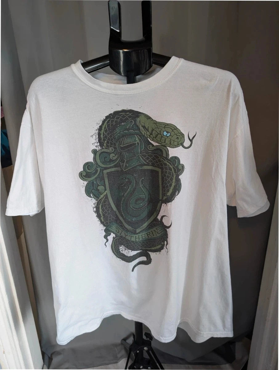 Harry Potter white graphic tee featuring green Slytherin crest and coiling snake design.