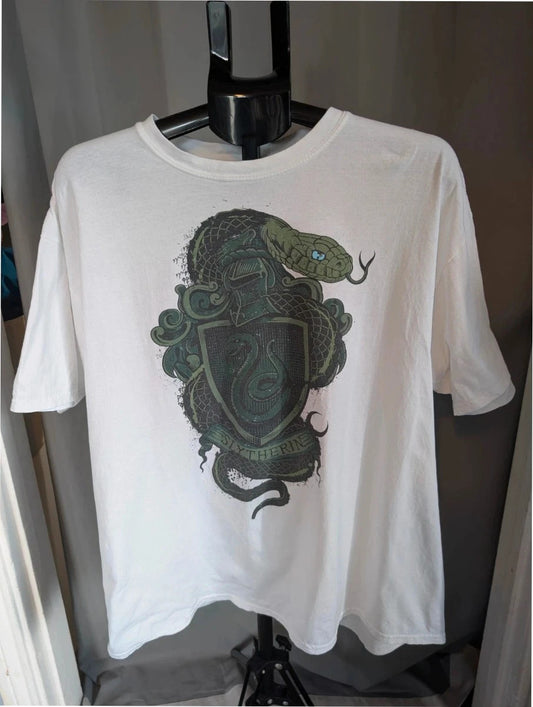 Harry Potter white graphic tee featuring green Slytherin crest and coiling snake design.