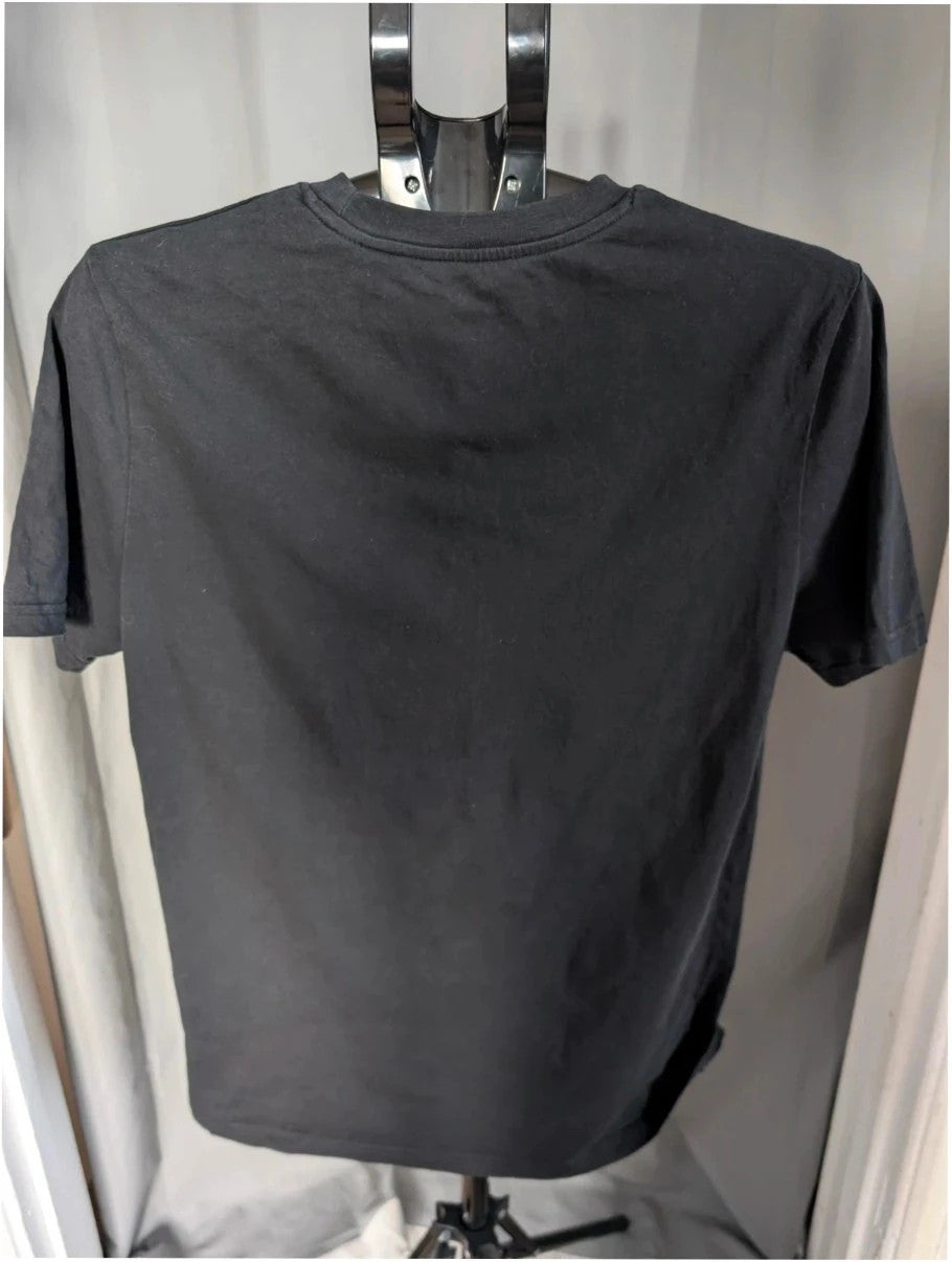 Stanley/Stella black graphic tee featuring Oasis logo and "Roll With It" beach print.