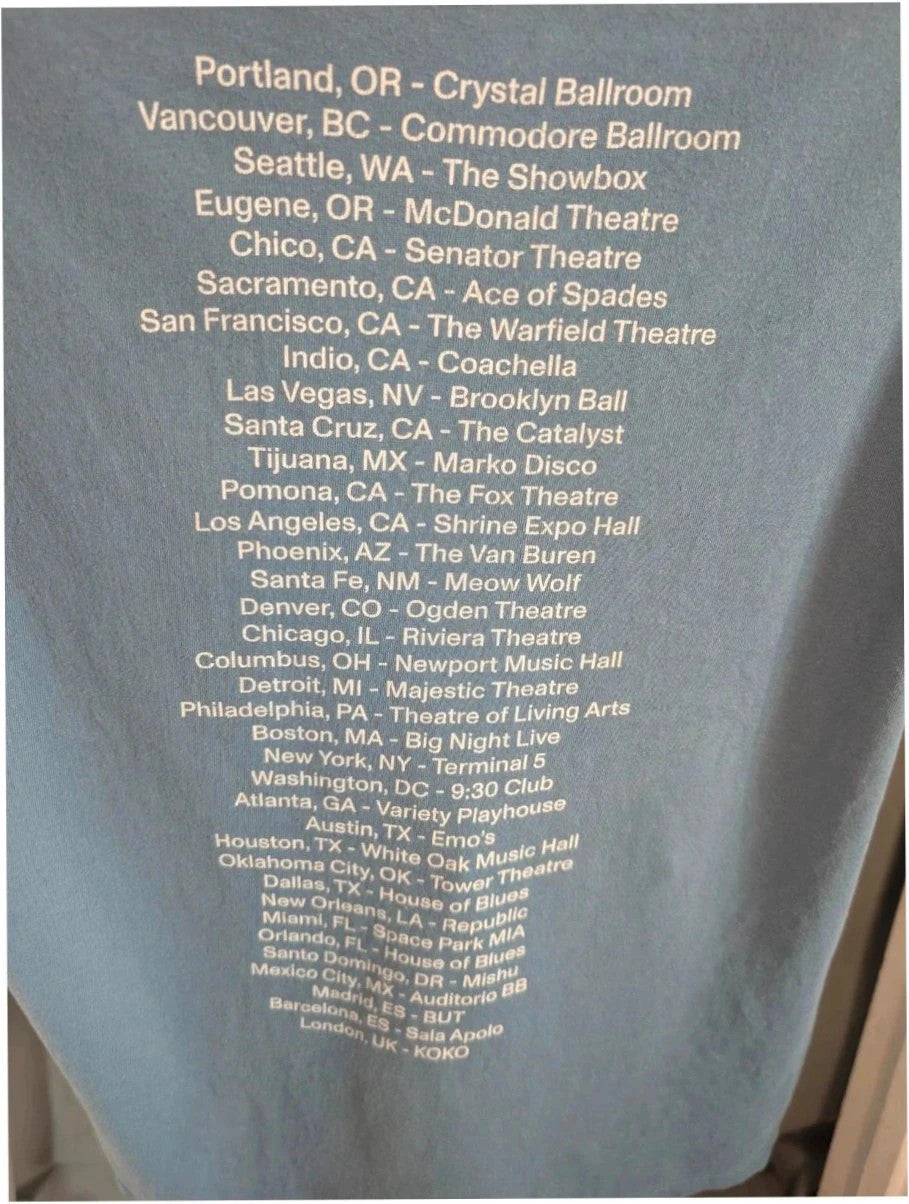 Omar Apollo blue graphic t-shirt with portrait print and tour date list on back.