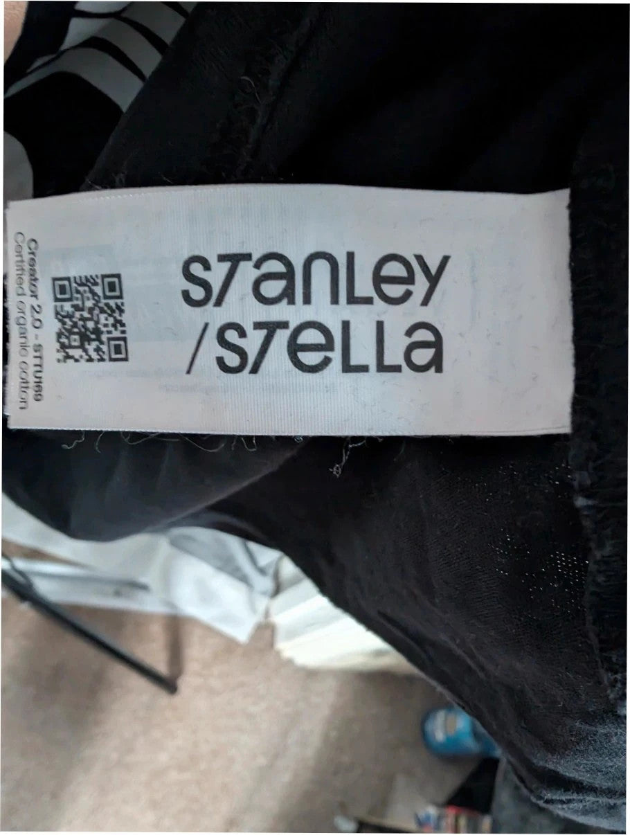Stanley/Stella black graphic tee featuring Oasis logo and "Roll With It" beach print.